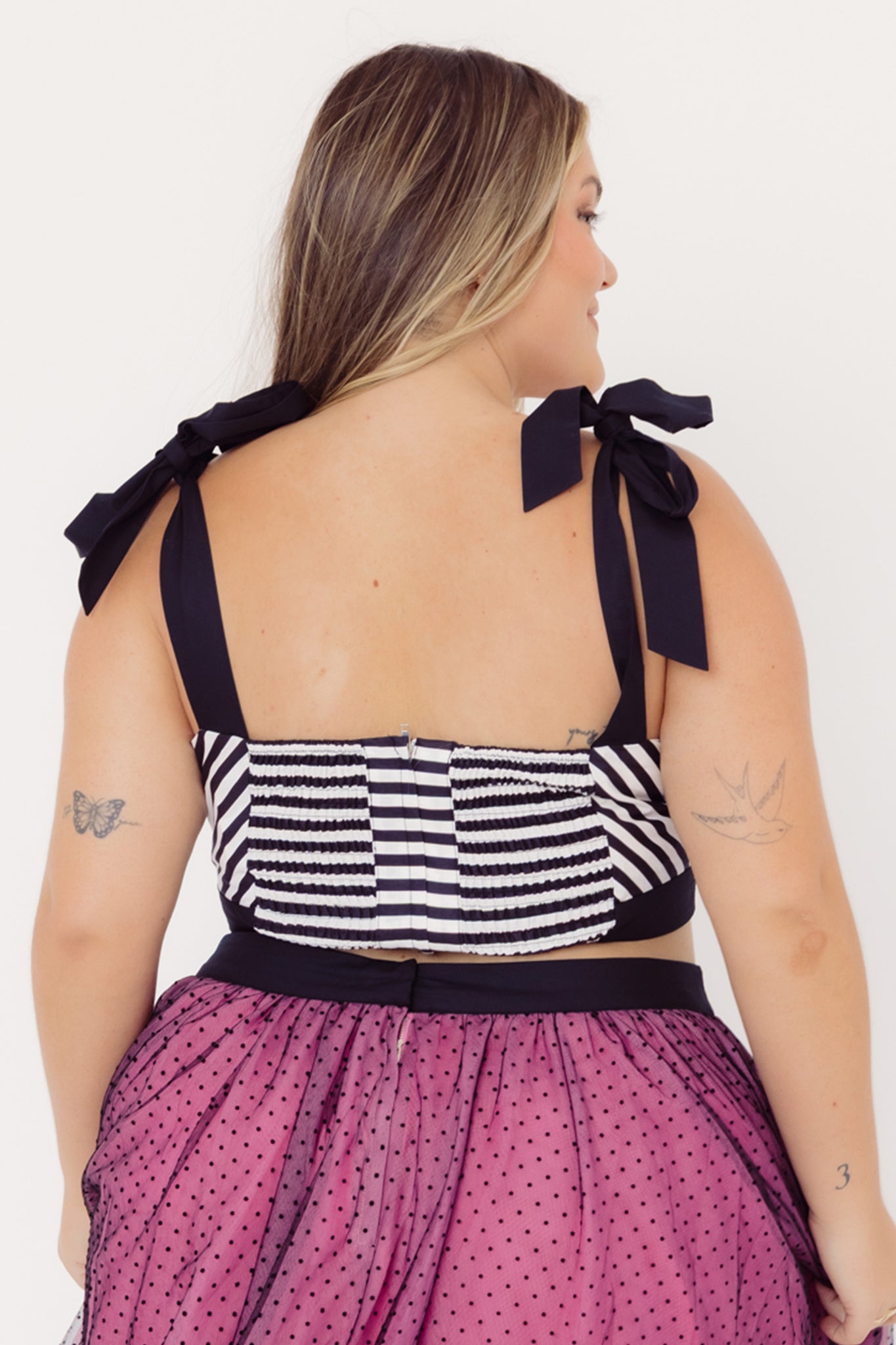 Mid-size woman wearing a Cherry Bobbins cotton black and white striped top with bow straps and a pink tulle skirt on a white background