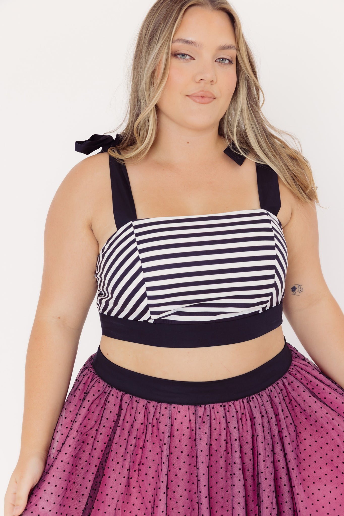 Front view of a mid-size woman wearing a Cherry Bobbins cotton striped top and pink tulle skirt with a white background