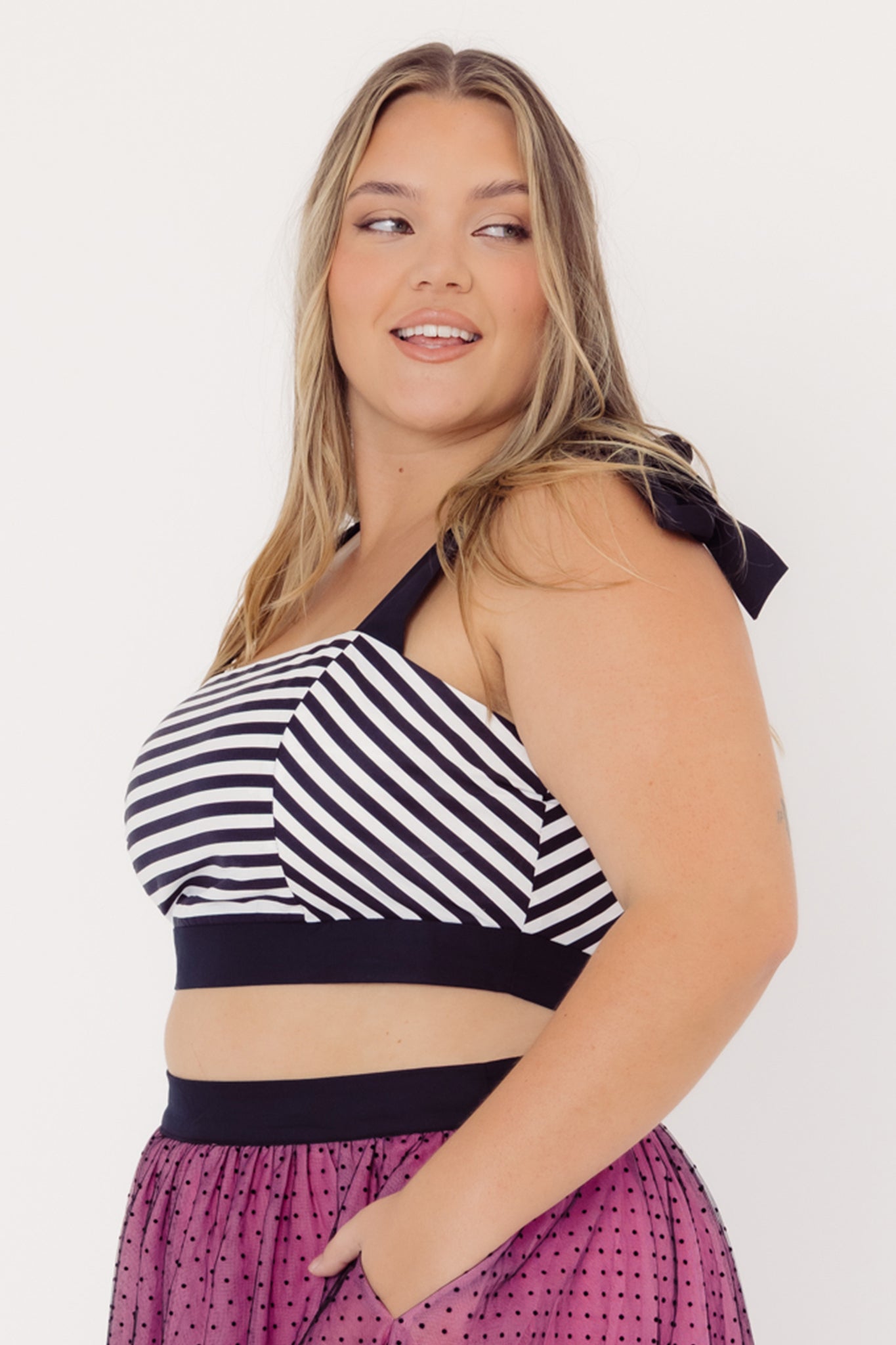 Side view of a mid-size woman wearing a Cherry Bobbins cotton striped top and pink tulle skirt on a white background