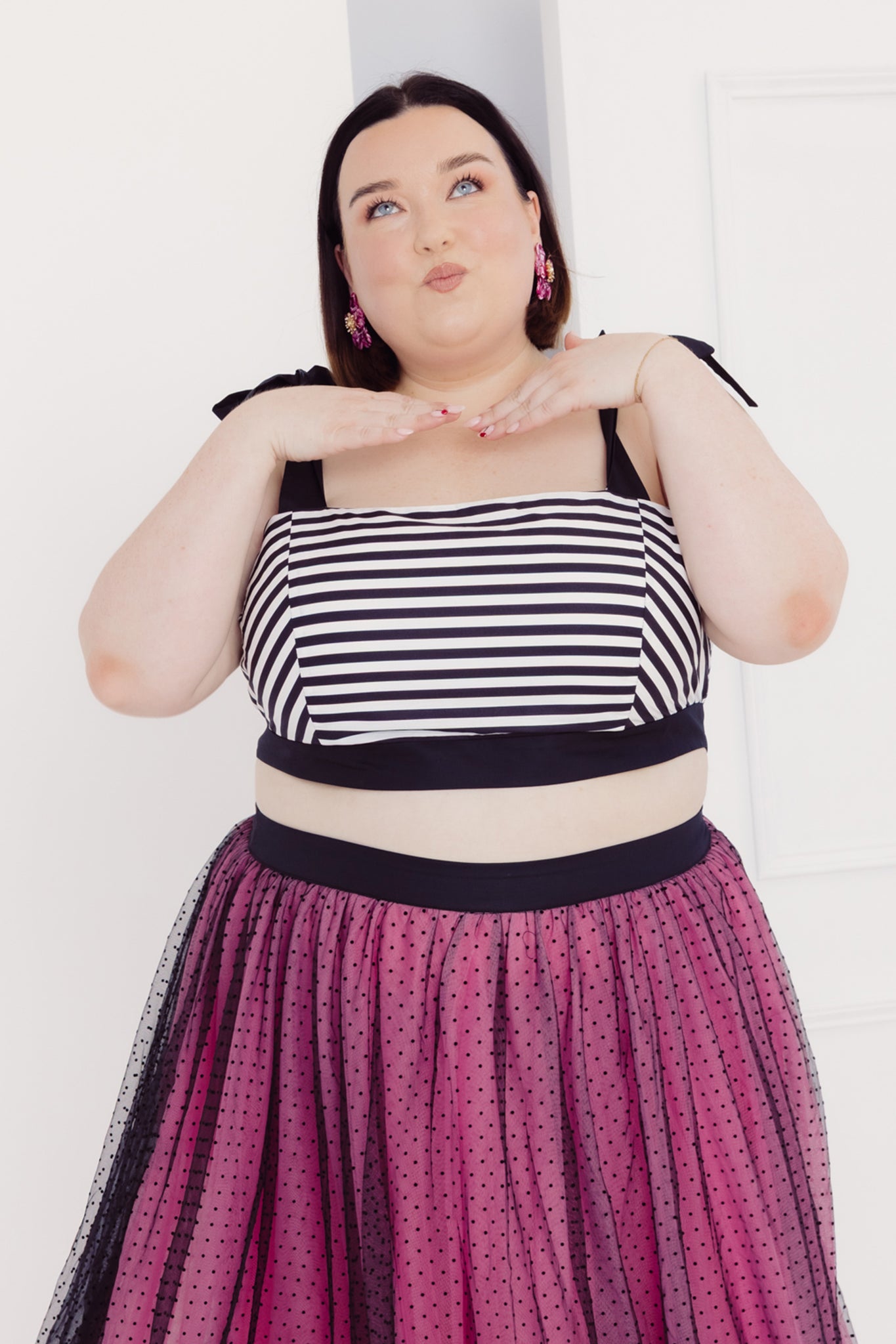 Plus size woman wearing a Cherry Bobbins black and white cotton striped top with a pink skirt against a white background