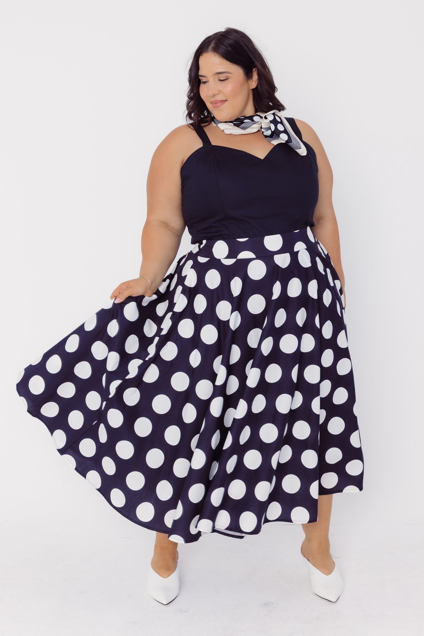 Front view of a woman wearing a Cherry Bobbins black top with white polka dots cotton skirt on a white background