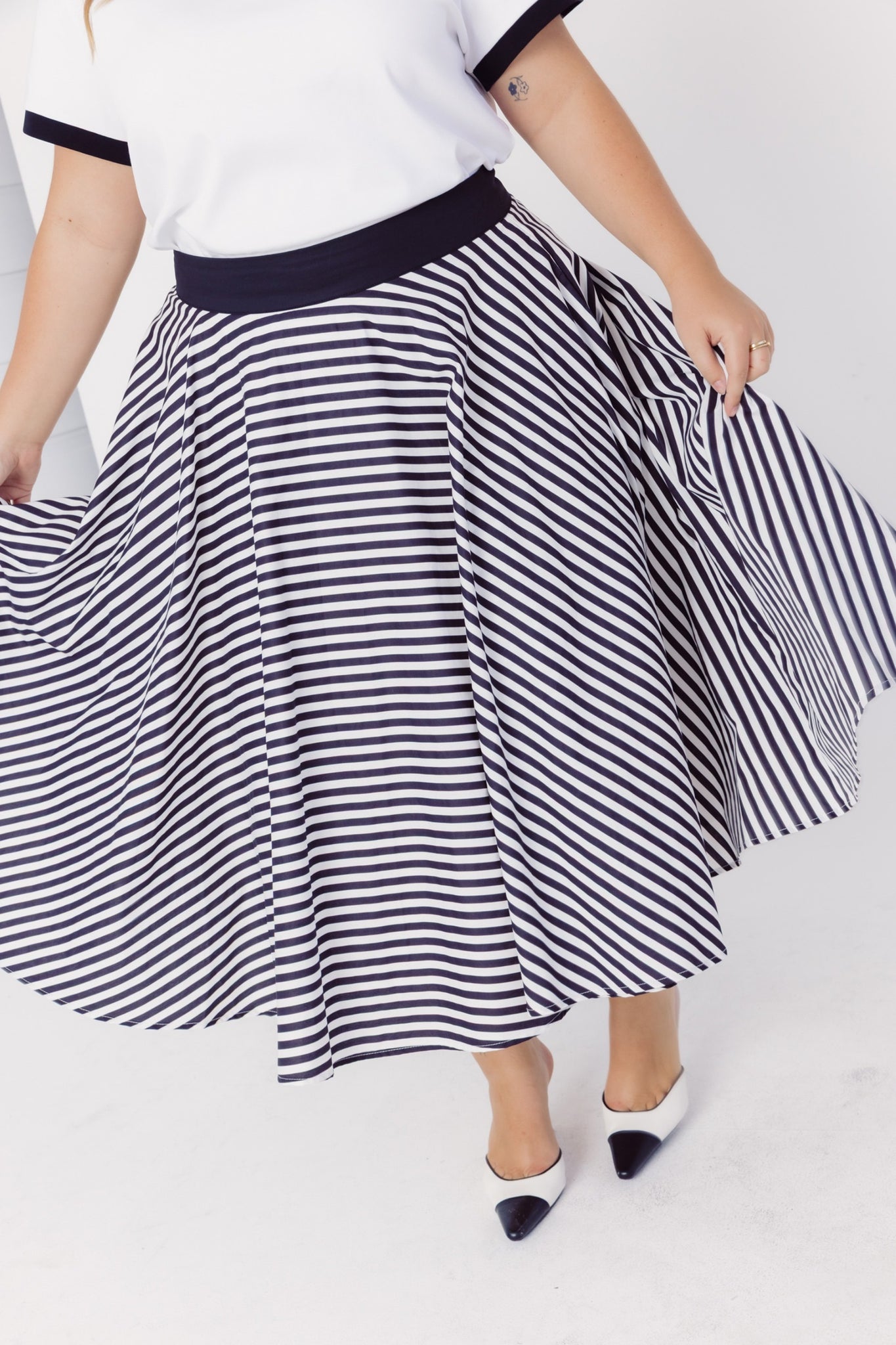 Close-up of a woman wearing a Cherry Bobbins black and white striped cotton skirt on a white background