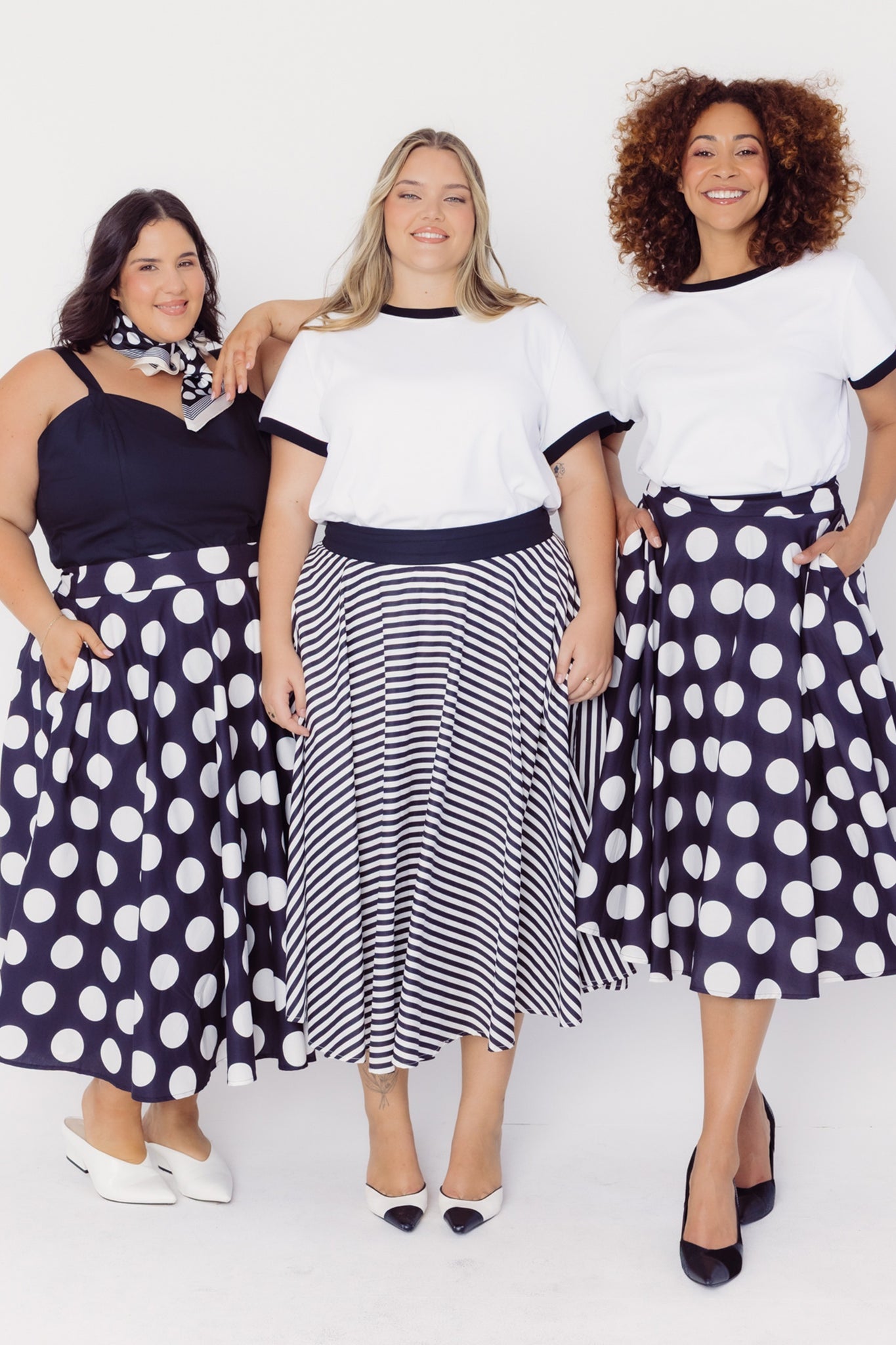 Three women wearing Cherry Bobbins polka dot and striped cotton skirts on a white background