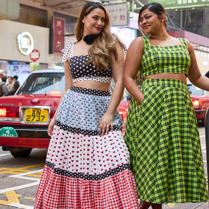 Two women in colourful dresses walking on a street with a red car in the background. Picture highlights Cherry Bobbins most coveted styles from their best sellers collection in square format.