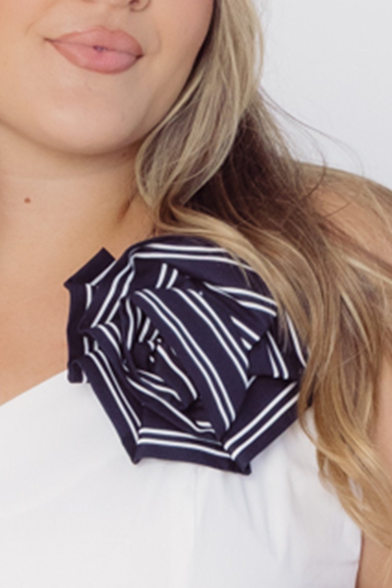 Woman wearing a Cherry Bobbins cotton white top with a black and white striped rose brooch 