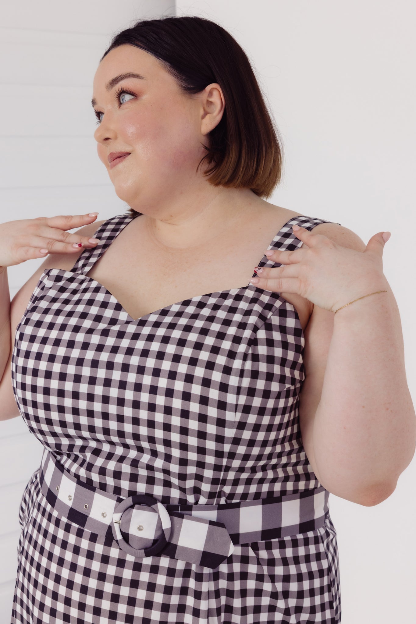 Woman wearing a black and white Cherry Bobbins checkered plus size dress against a plain background