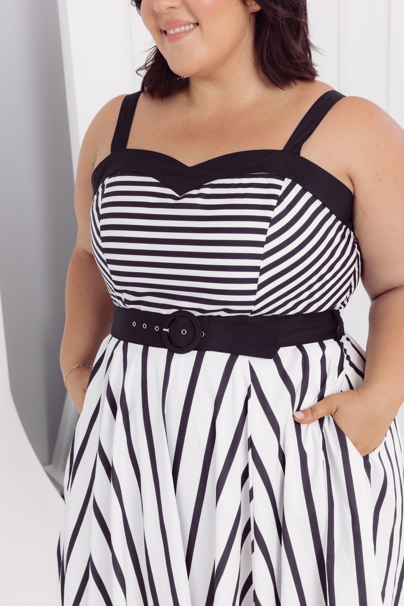 Detailed image of a woman wearing a Cherry Bobbins black and white striped cotton midi dress with a belt against a plain background