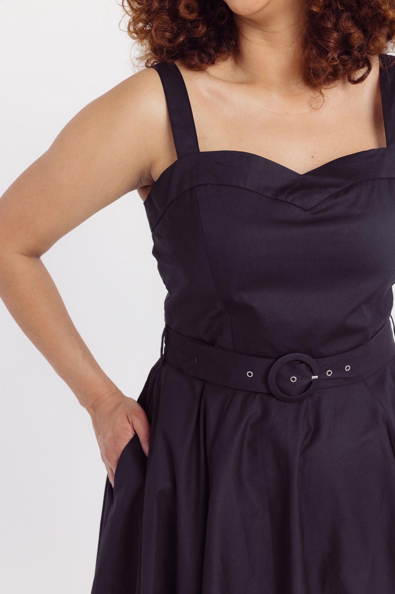 Close up details of a woman wearing a Cherry Bobbins plain cotton black dress with a belt on a white background