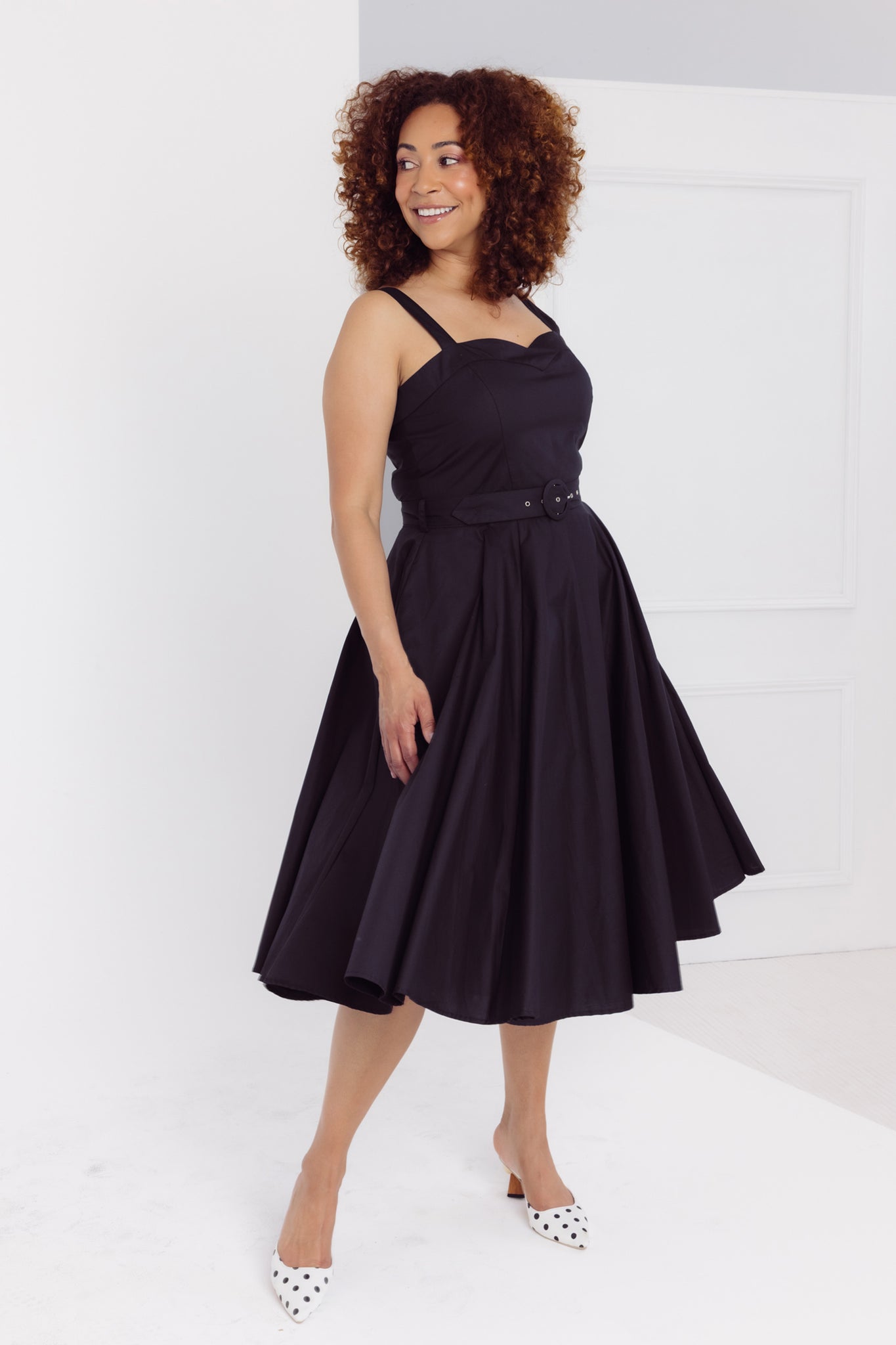 Front side view of a woman wearing a Cherry Bobbins plain black midi dress