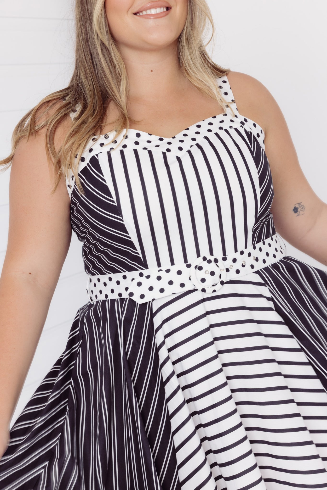 Mid-size woman wearing a Cherry Bobbins black and white striped cotton midi dress with polka dot accents against a plain background
