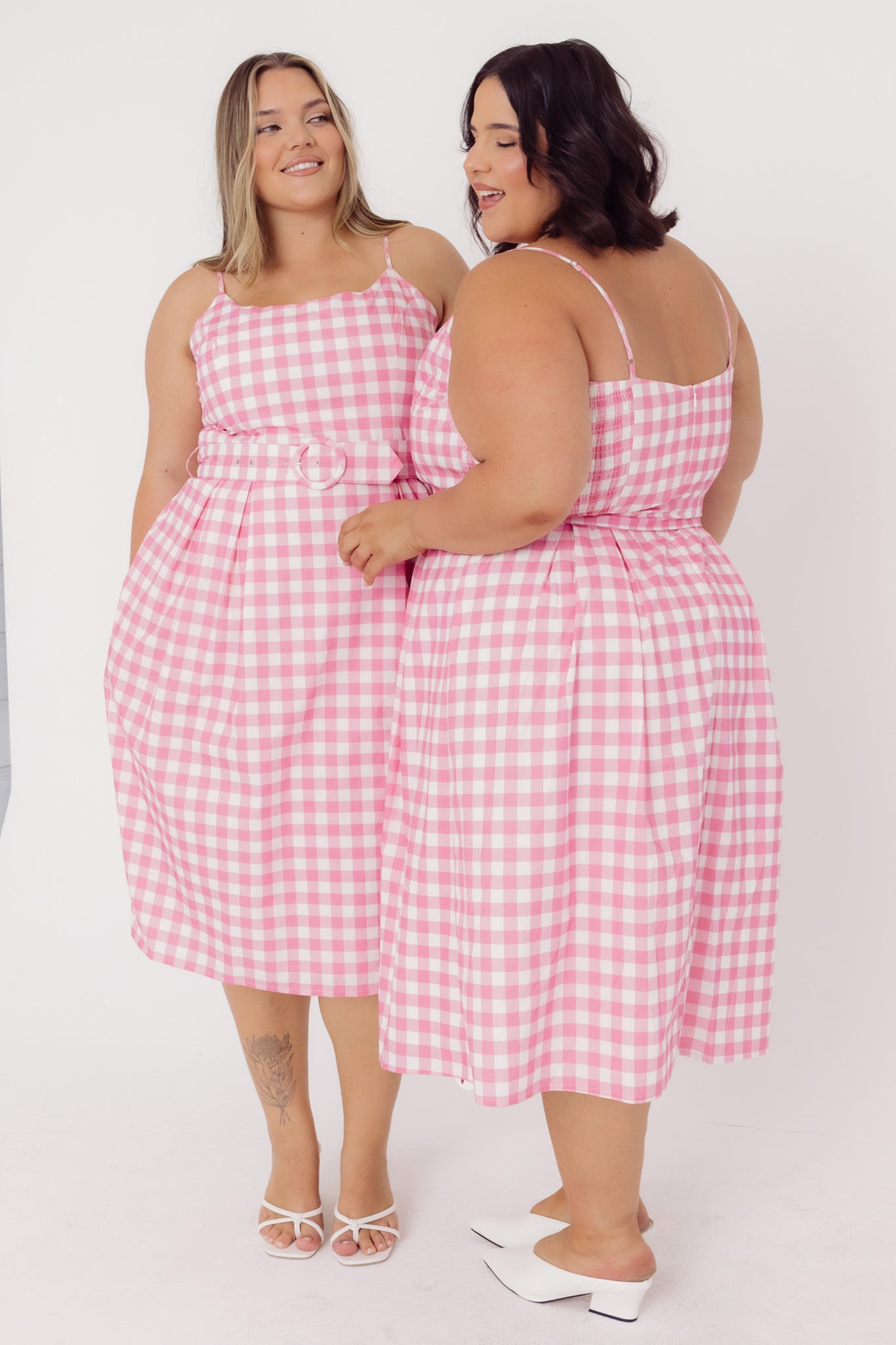 Two women wearing Cherry Bobbins cotton pink gingham dresses against a white background