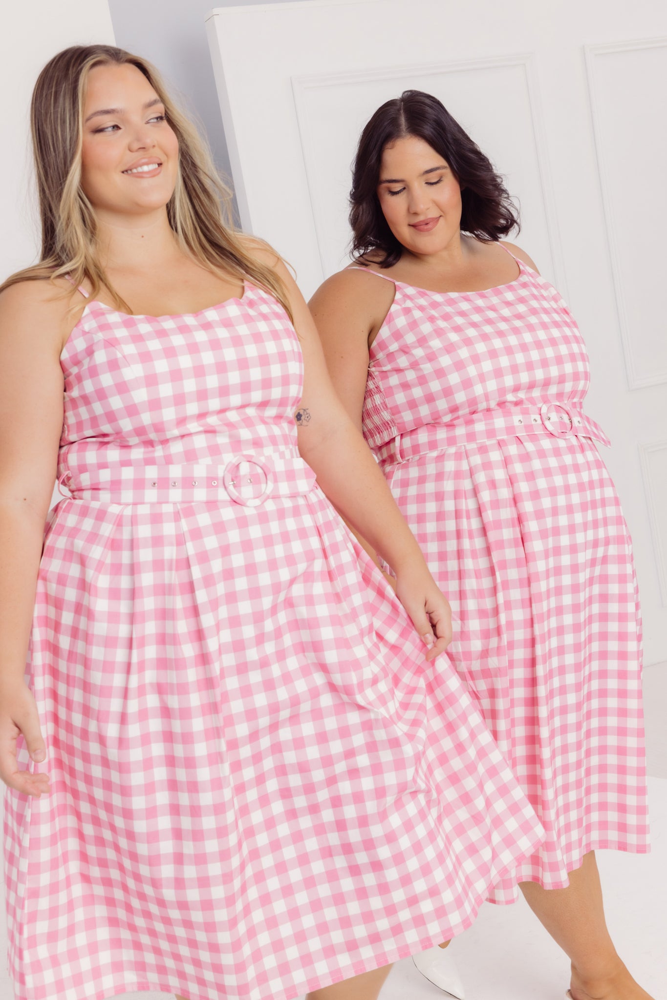 Two women wearing Cherry Bobbins pink gingham dresses against a white background