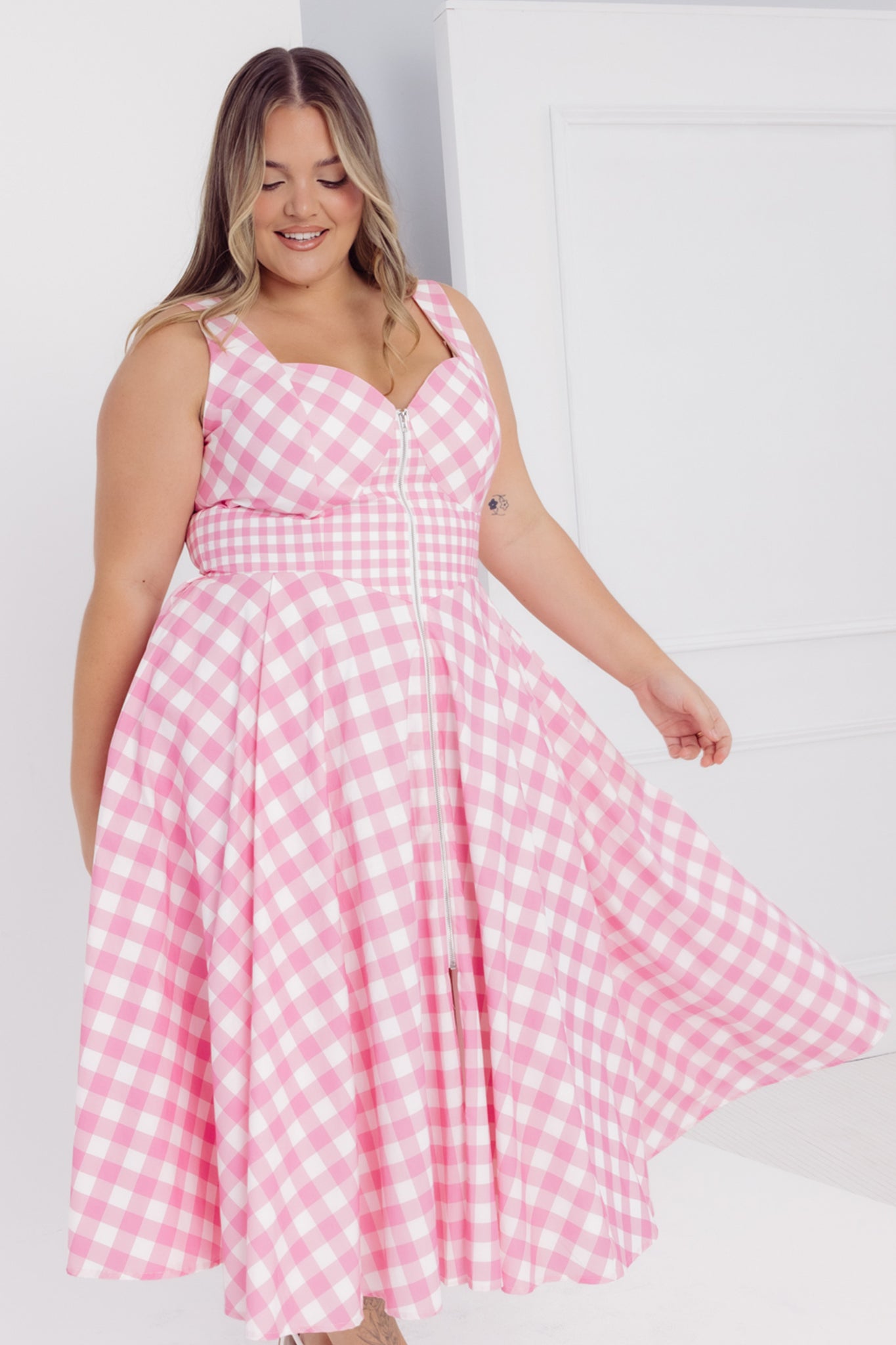 Woman wearing a Cherry Bobbims pink and white gingham midi cotton dress against a white background