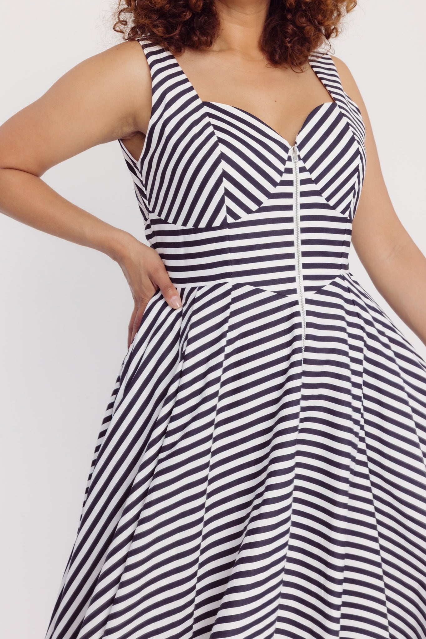 Close up image of a woman wearing a Cherry Bobbins black and white striped cotton midi dress against a white background