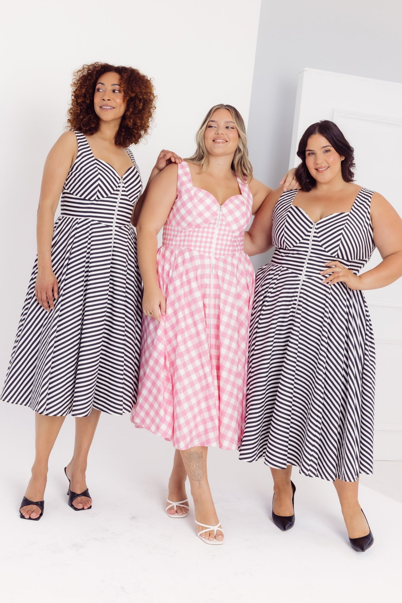 Three women wearing different printed Cherry Bobbins Taylor cotton midi dresses on a white background