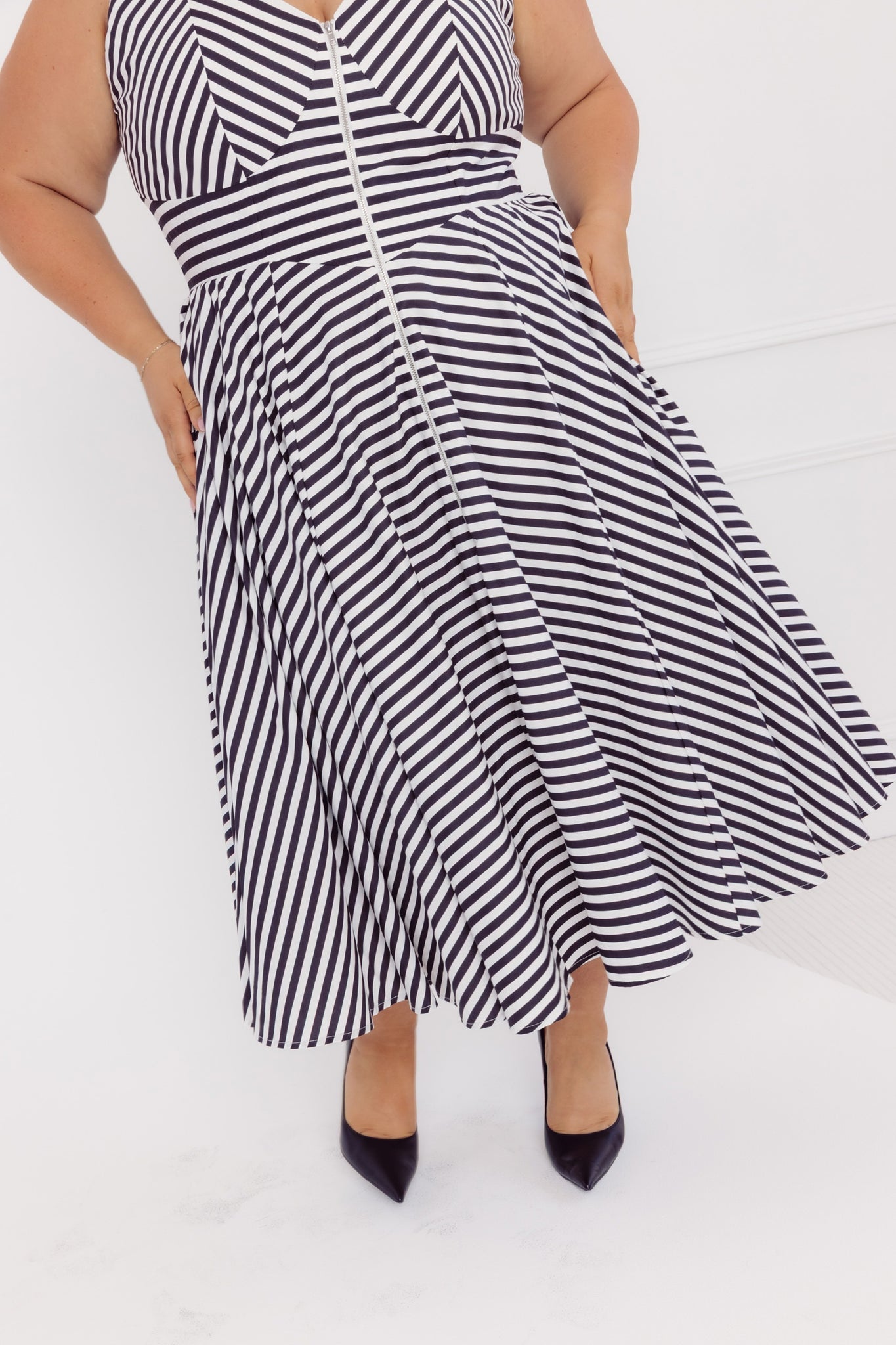 Close up image of a plus size woman wearing a Cherry Bobbins black and white striped cotton midi dress on a white background