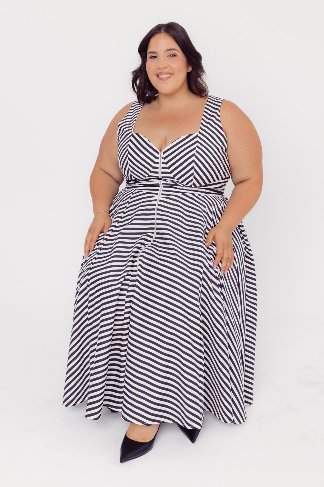 Plus size woman wearing a Cherry Bobbins black and white striped cotton midi dress, while sitting, on a white background
