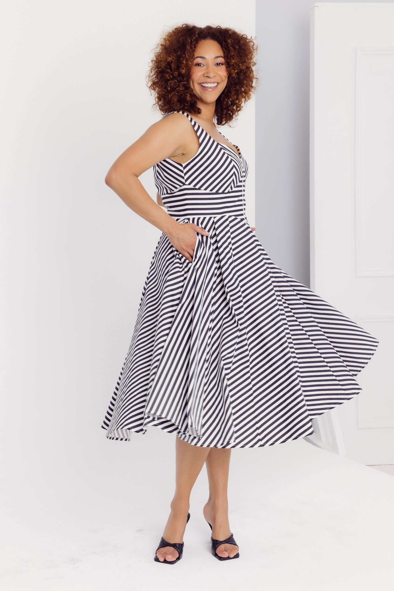 Woman twirling her Cherry Bobbins black and white striped cotton midi dress against a white background