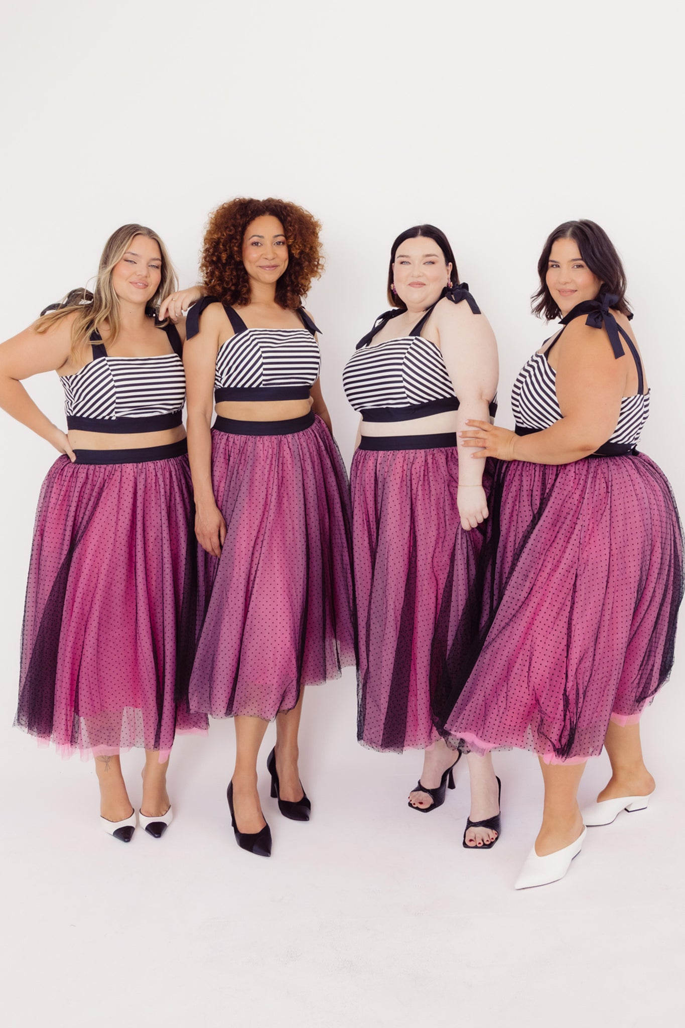 Four women wearing matching Cherry Bobbins cotton and tulle outfits with a white background
