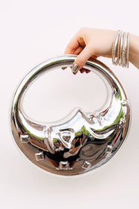 Hand holding a silver moon face bag made from a reflective material