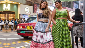 Two women in colourful dresses walking on a street with a red car in the background. Picture highlights Cherry Bobbins most coveted styles from their best sellers collection in banner format. 